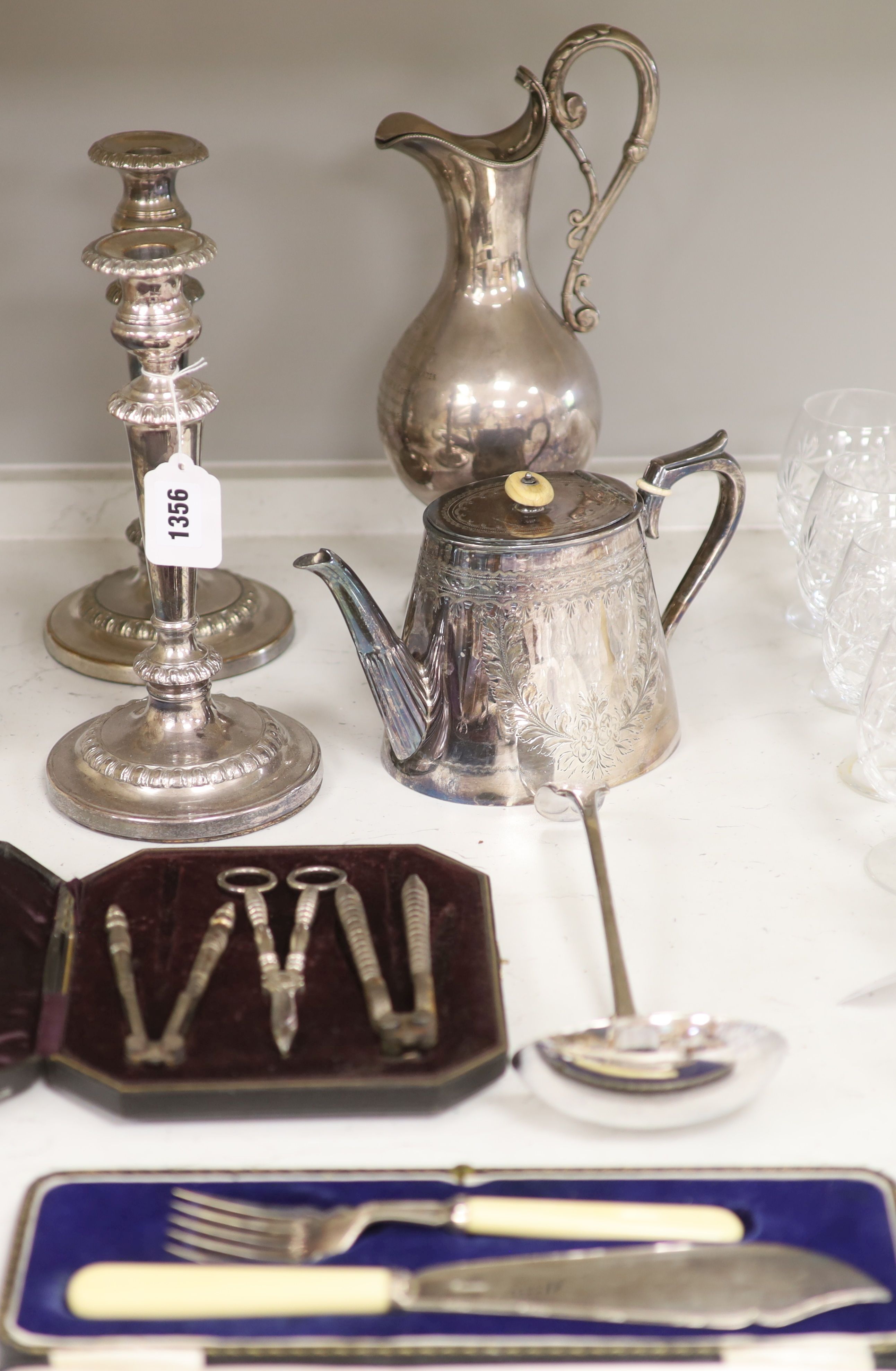 A pair of plated candlesticks, a wine ewer, height 33cm (dented), teapot, ladle, cased nutcrackers